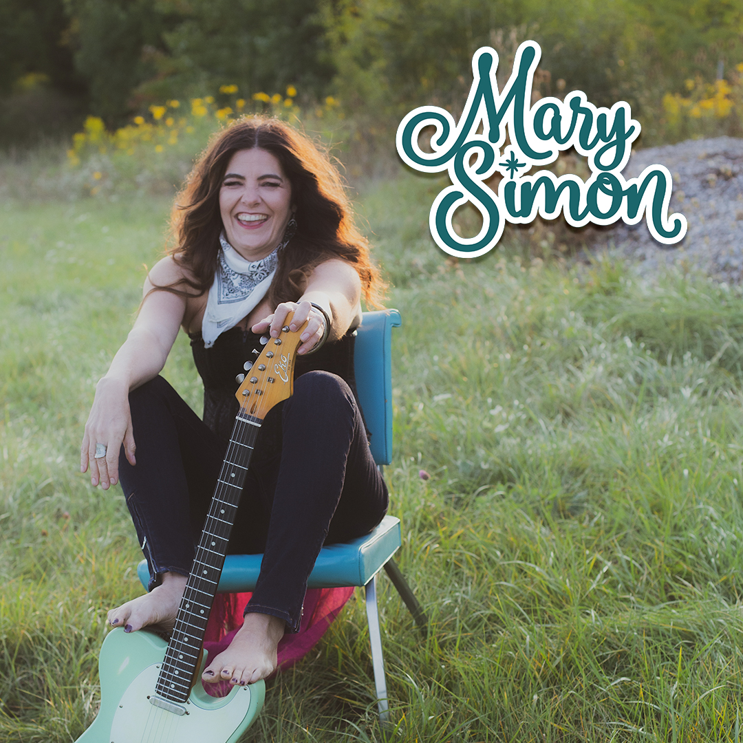 Mary Simon Sitting outside on a chair with her guitar
